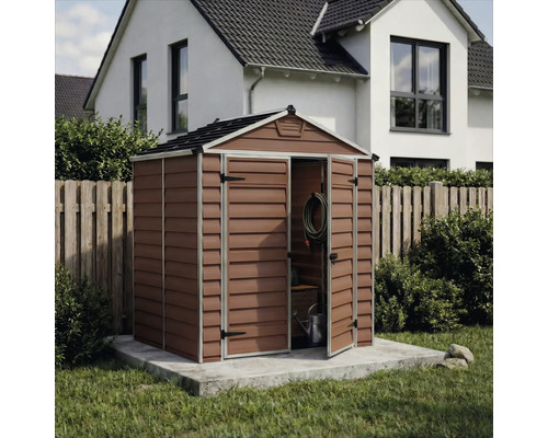 Abri de jardin en plastique avec toit à deux pans et double porte ouverte sur une base en béton dans un jardin organisé.