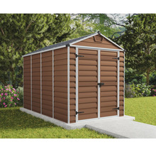 Abri de jardin brun avec toit à deux pans et double porte battante sur une fondation en béton clair dans un jardin soigné avec pelouse et arbres.