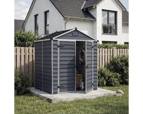 Abri de jardin en plastique anthracite avec toit à deux pans et double porte, installé sur une dalle en béton dans un jardin.