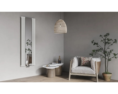 Radiateur design vertical avec miroir intégré dans un salon moderne et lumineux avec fauteuil, tables d'appoint et plante d'intérieur.