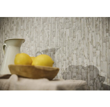 Papier peint intissé avec motif de blocs de pierre abstraits dans une pièce lumineuse derrière un pichet et un bol en bois avec des citrons.