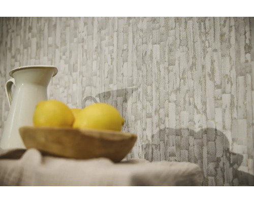 Papier peint intissé avec motif de blocs de pierre abstraits dans une pièce lumineuse derrière un pichet et un bol en bois avec des citrons.