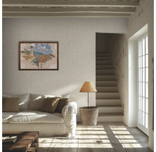 Salon lumineux avec papier peint texturé, canapé blanc, coussins marron, parquet, lampe sur un panier et escalier.