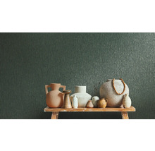 Papier peint intissé vert foncé à texture verticale derrière divers vases en céramique sur un banc en bois.