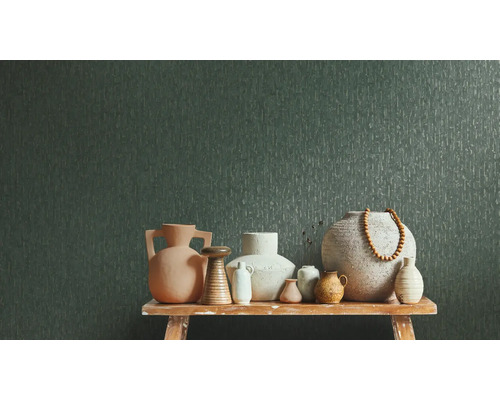 Papier peint intissé vert foncé à texture verticale derrière divers vases en céramique sur un banc en bois.