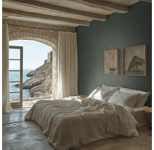 Chambre à coucher avec papier peint texturé vert foncé, lit blanc, plafond avec poutres en bois et une arche en pierre avec vue sur la mer.