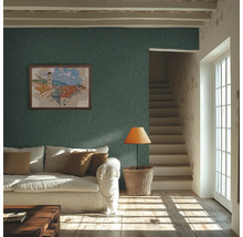 Salon rustique avec papier peint texturé bleu pétrole, canapé blanc, escalier en bois et lumière naturelle par une fenêtre à croisillons.