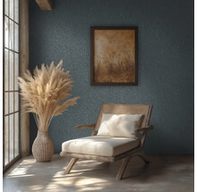 Pièce rustique avec mur texturé, chaise en bois et rotin, vase avec herbe de la pampa et tableau encadré sous la lumière naturelle.
