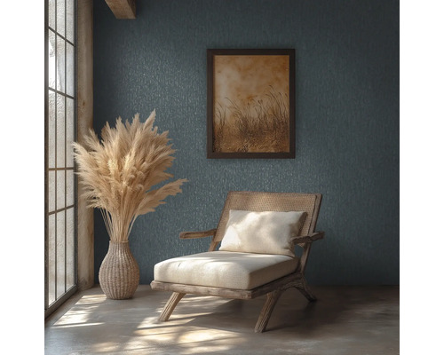 Pièce rustique avec mur texturé, chaise en bois et rotin, vase avec herbe de la pampa et tableau encadré sous la lumière naturelle.