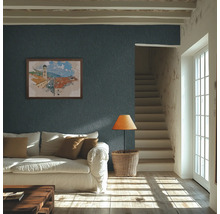 Salon lumineux avec papier peint texturé bleu foncé au mur, canapé blanc et lumière naturelle sur le parquet.