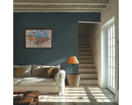 Salon lumineux avec papier peint texturé bleu foncé au mur, canapé blanc et lumière naturelle sur le parquet.