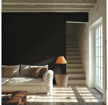 Salon avec papier peint mural texturé, canapé, table en bois, lampadaire et escalier à côté d'une fenêtre lumineuse.