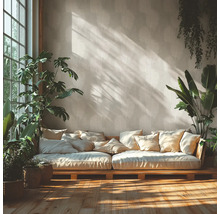 Salon lumineux avec papier peint à motif de feuilles de palmier, canapé bas en bois avec coussins, plantes d'intérieur et lumière naturelle.