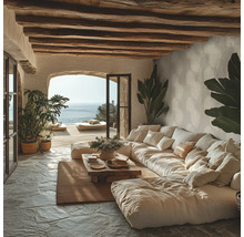 Salon rustique avec grand canapé modulable, poutres en bois au plafond, sol en pierre et vue sur la mer via une ouverture en arche.