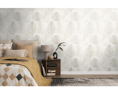 Chambre à coucher lumineuse avec papier peint intissé à motif de feuilles de palmier, un lit avec des coussins et une table de chevet.