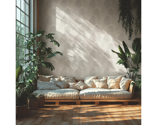 Salon lumineux avec papier peint à motif de feuilles, canapé en bois avec de nombreux coussins et diverses plantes d intérieur sur parquet.