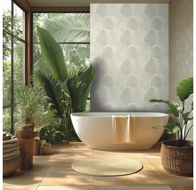 Salle de bains lumineuse avec baignoire îlot blanche, papier peint motif feuilles de palmier, grandes plantes vertes et tapis rond en fibres.