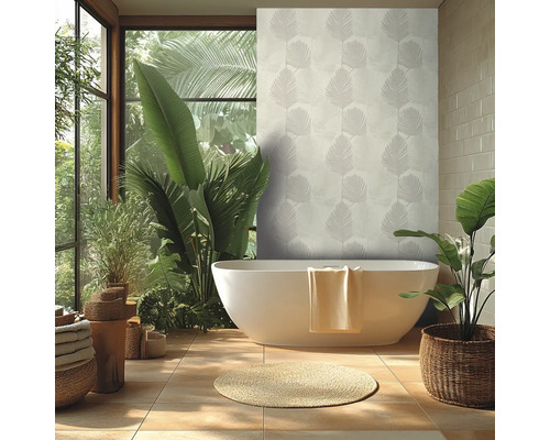 Salle de bains lumineuse avec baignoire îlot blanche, papier peint motif feuilles de palmier, grandes plantes vertes et tapis rond en fibres.
