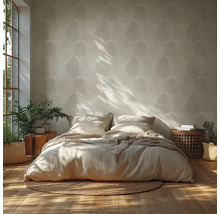 Chambre lumineuse avec papier peint à motif de feuilles, lit bas avec literie neutre sur un tapis rond en jute et accents en bois.