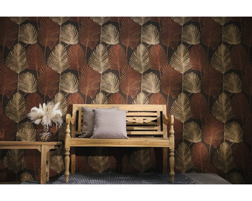 Vliestapete mit großem Palmblatt-Muster in Erdtönen hinter einer Holzbank mit Kissen und einem Beistelltisch mit Vase.