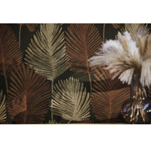 Vliestapete mit großflächigem Palmenblatt Muster in Gold und Bronze vor dunklem Hintergrund.