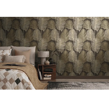 Papier peint intissé avec motif de grandes feuilles dans une chambre à coucher moderne avec lit et table de chevet.