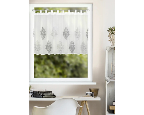 Brise-bise blanc à pattes avec motif d'ornement gris sur une fenêtre au-dessus d'un bureau clair.