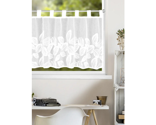 Rideau brise-bise blanc à motif de feuilles avec passants et bord festonné devant une fenêtre dans un bureau clair et ordonné.