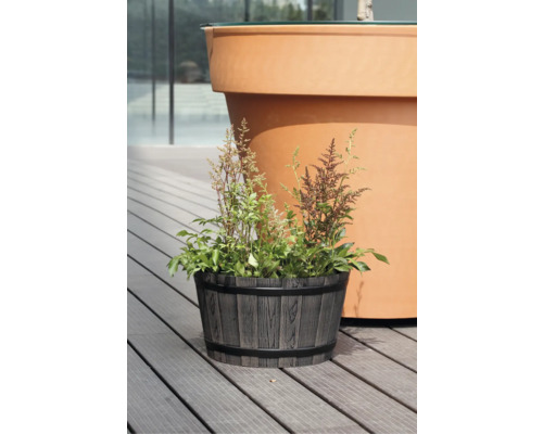 Pflanzkübel in Holzoptik und Fassform mit Pflanzen auf einer Holzterrasse.