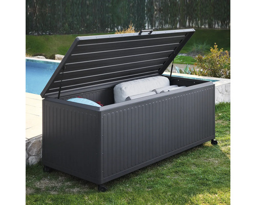 Dunkelgraue Garten-Auflagenbox aus Metall mit offenem Deckel und Rollen, gefüllt mit Sitzkissen, am Pool im Garten.