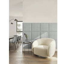 Salon moderne et lumineux avec des panneaux muraux carrés rembourrés en tissu bleu clair à côté d un fauteuil rond en tissu bouclé blanc.