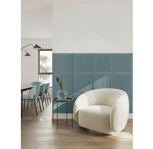 Modernes, helles Wohnzimmer mit blauen gepolsterten Wandpaneelen aus Textil hinter einem weißen Sessel.