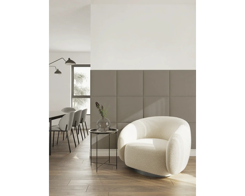 Salon moderne avec un mur de panneaux acoustiques carrés beige-brun, un fauteuil rond crème et un coin repas à l'arrière-plan.