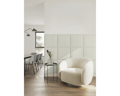 Aménagement intérieur moderne et lumineux avec panneaux muraux carrés, un fauteuil bouclé rond et un coin repas à l'arrière-plan.