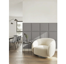 Salon moderne avec panneaux muraux rembourrés carrés gris, fauteuil blanc et table d’appoint sur parquet.