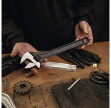 Grande clé à molette noire en acier chrome-vanadium d'une longueur de 375 millimètres sur un établi avec des outils.