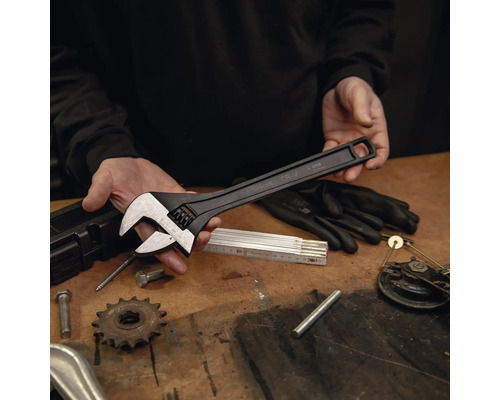 Grande clé à molette noire en acier chrome-vanadium d'une longueur de 375 millimètres sur un établi avec des outils.