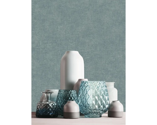 Papier peint intissé avec une structure textile fine bleu-vert, décoré de divers vases en céramique et en verre.