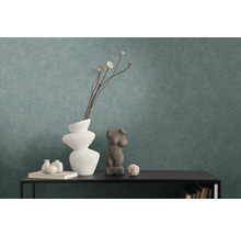 Papier peint intissé texturé de couleur pétrole derrière une console noire avec des vases décoratifs et des sculptures.