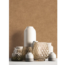 Papier peint uni texturé beige derrière un groupe décoratif de différents vases blancs et en verre.