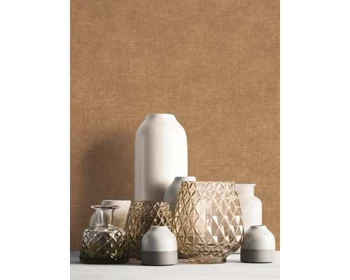 Papier peint uni texturé beige derrière un groupe décoratif de différents vases blancs et en verre.