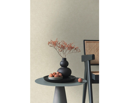 Papier peint intissé structuré beige dans une pièce moderne avec table basse, vase de fleurs séchées et chaise.
