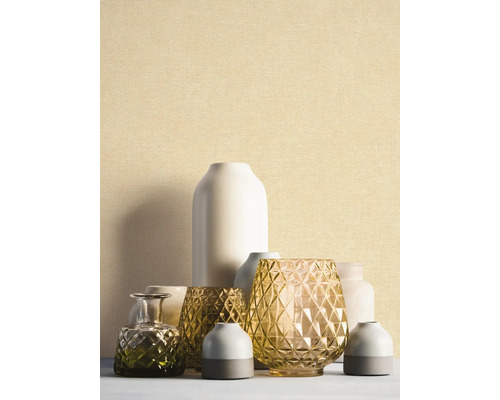 Papier peint à structure fine beige clair derrière un groupe de vases décoratifs en verre et en céramique.