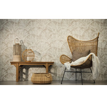Salon avec papier peint intissé à motif d'éventail, fauteuil en rotin avec plaid, banc en bois avec lanternes et un panier tressé au sol.