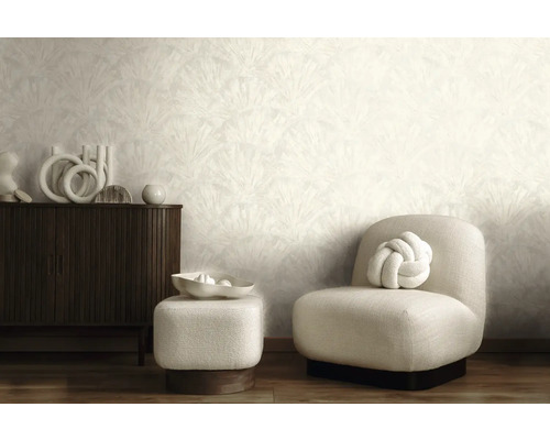 Salon moderne avec papier peint clair à motifs, buffet en bois sombre, fauteuil rembourré clair et pouf assorti.