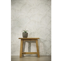Papier peint avec motif de feuilles en éventail, tabouret en bois avec plante grasse en pot devant un mur clair.
