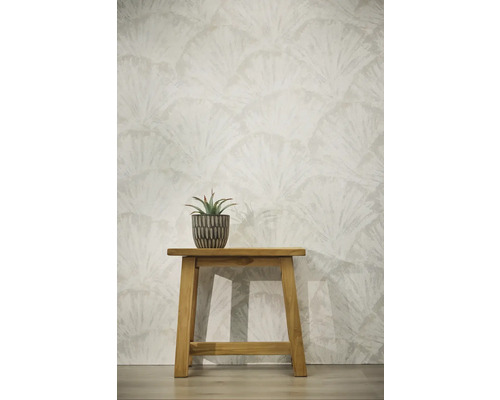 Papier peint avec motif de feuilles en éventail, tabouret en bois avec plante grasse en pot devant un mur clair.