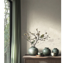 Salon lumineux avec buffet en bois, vases en céramique verte avec des branches devant un mur à peinture structurée et des rideaux.