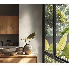 Cuisine moderne lumineuse, meubles en bois, bols en céramique et vase sur surface en bois devant une fenêtre avec vue sur des plantes vertes.