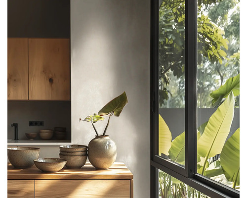 Cuisine moderne lumineuse, meubles en bois, bols en céramique et vase sur surface en bois devant une fenêtre avec vue sur des plantes vertes.